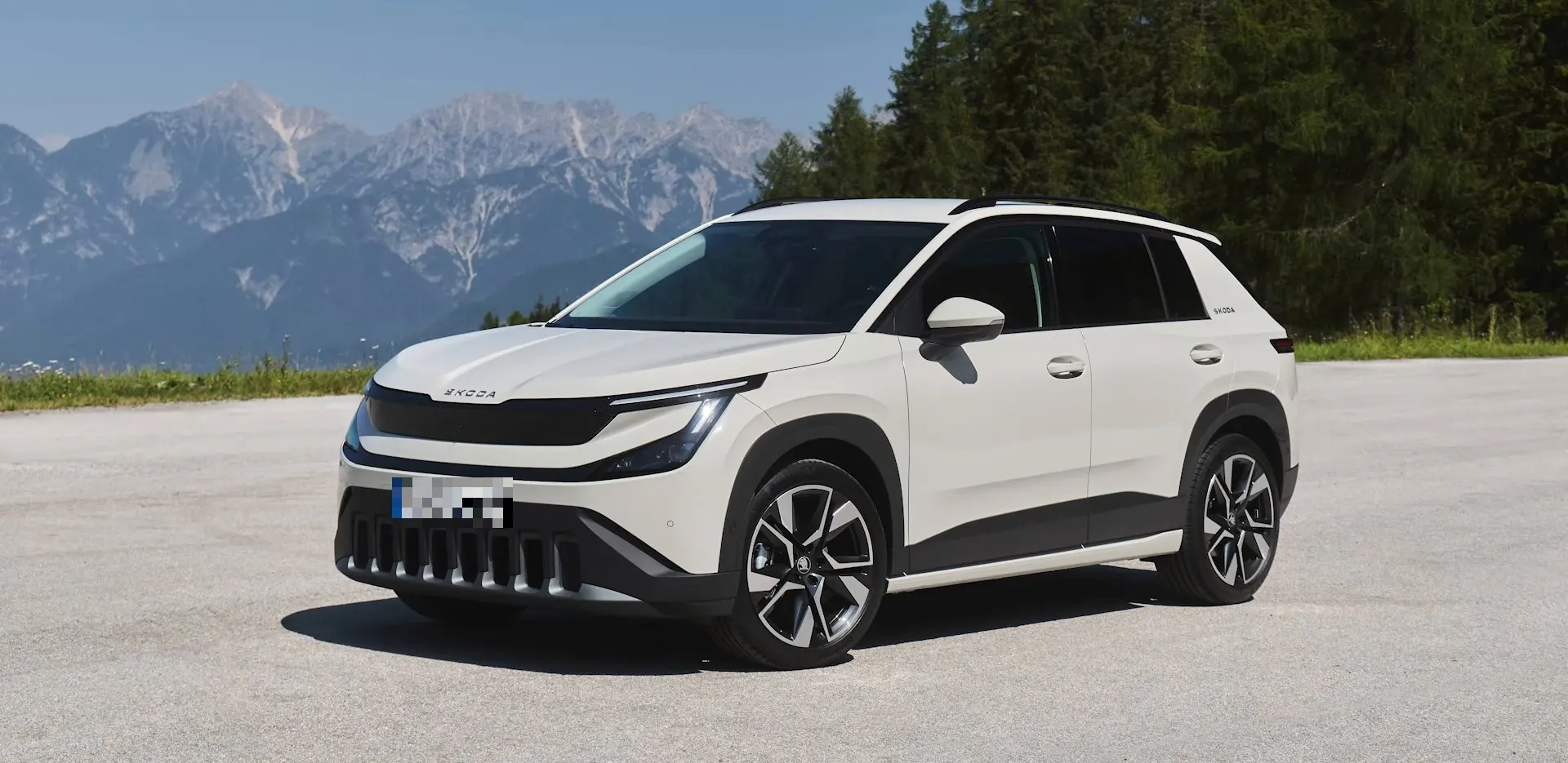 Weißer Skoda Epiq auf einem Parkplatz vor Bergkulisse